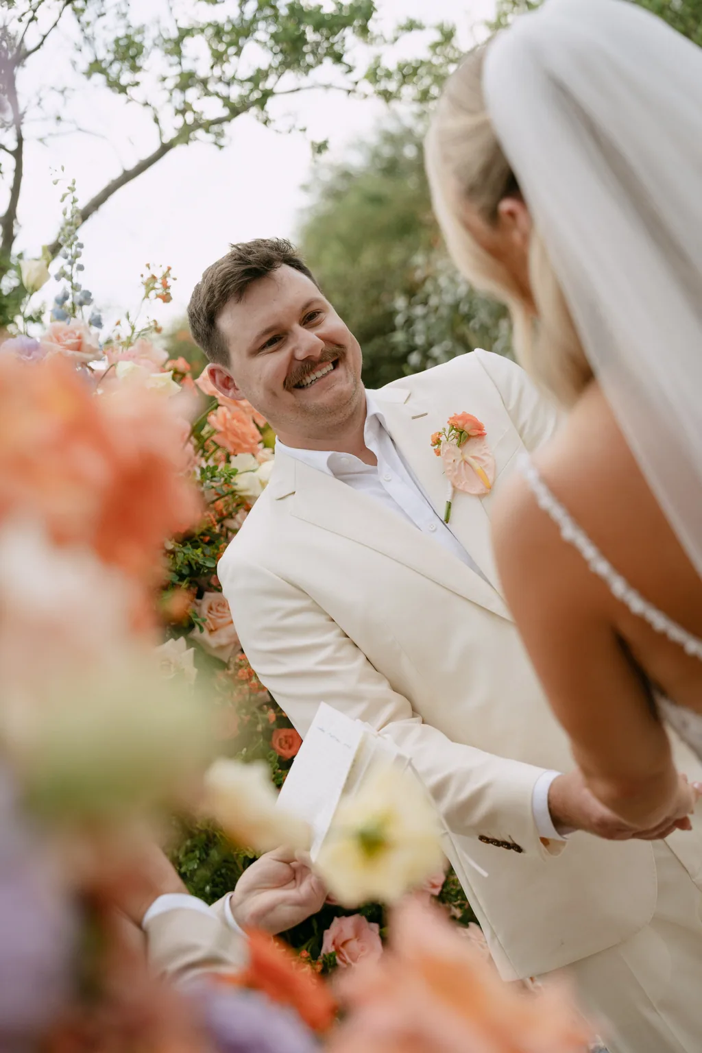 Matthew laughing during the ceremony, the flowers out of focus in front