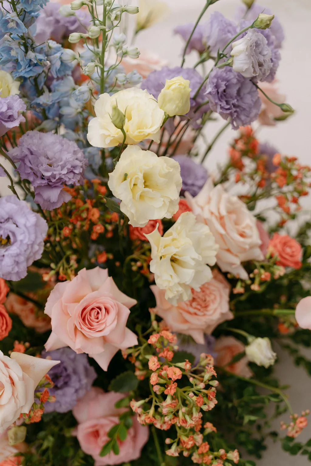 The wedding flowers up close: peach roses, lilac lisianthus, blue delphinium