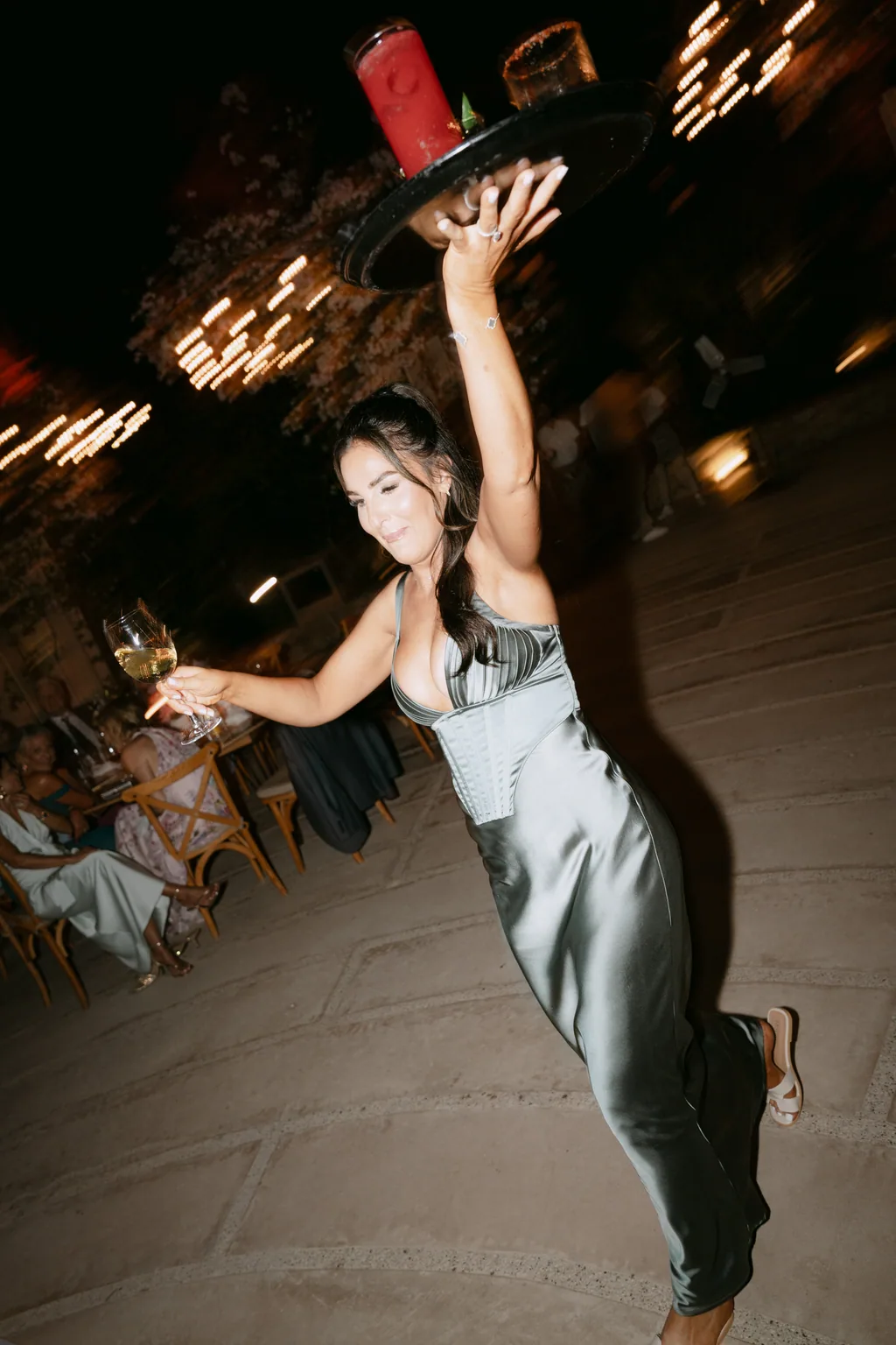 A guest carrying a tray of drinks across the party under the lights