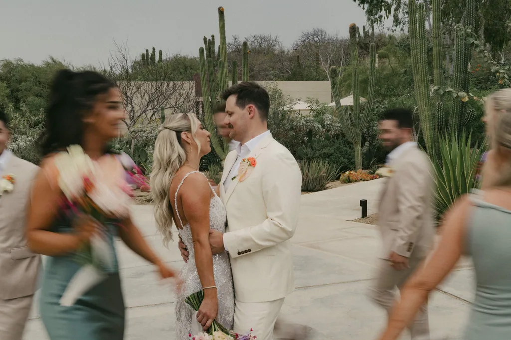 Bailey and Matthew stand still, face to face, while the wedding party streams past them at Acre, San José del Cabo