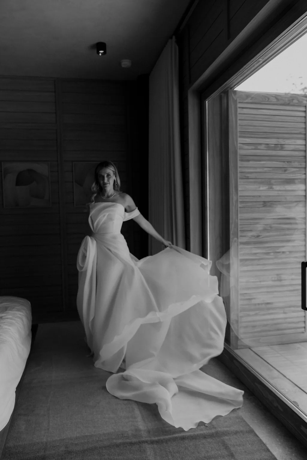 At the window with the dress pooled on the floor, in black and white