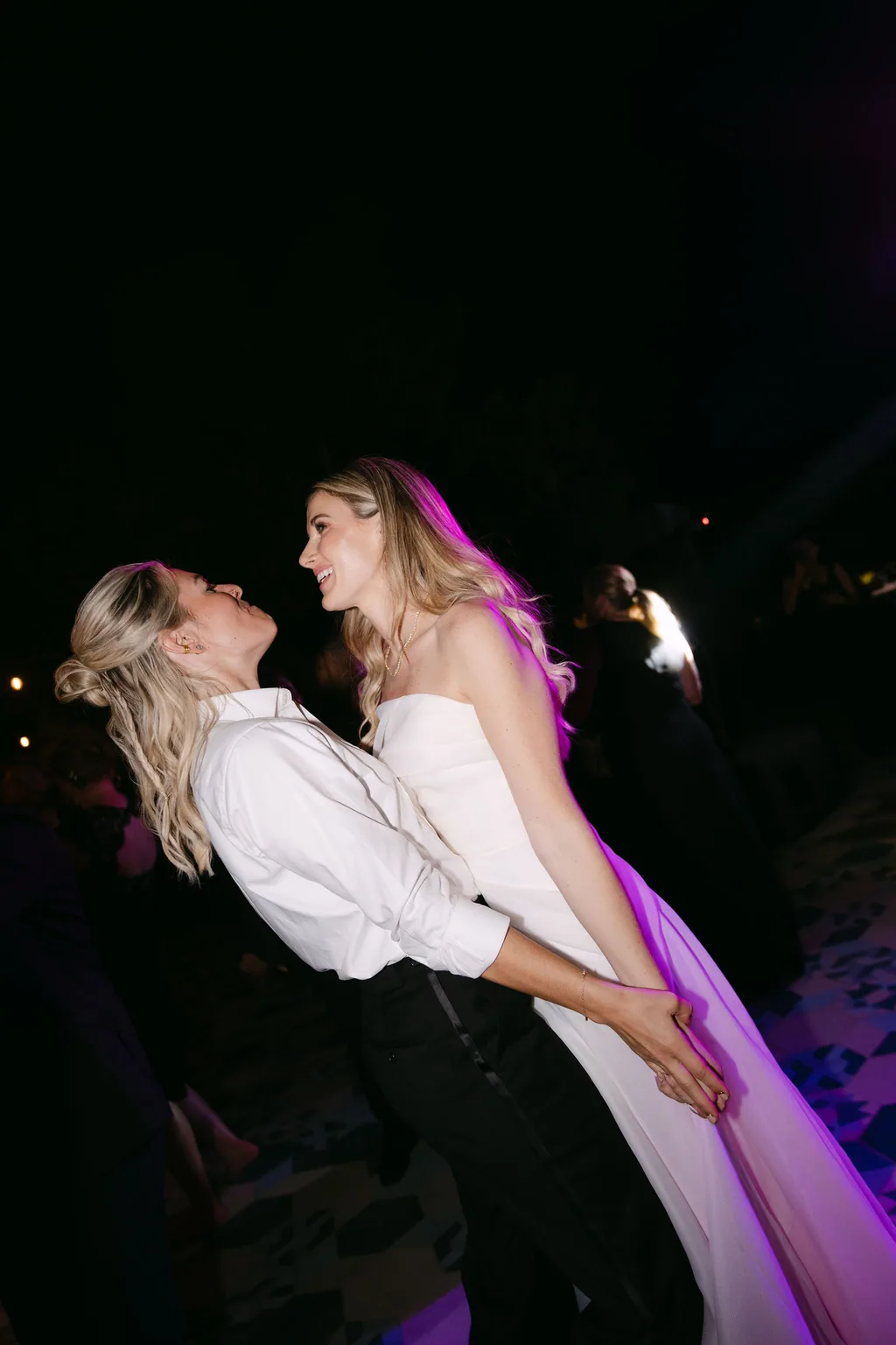 A dip on the dance floor under magenta light