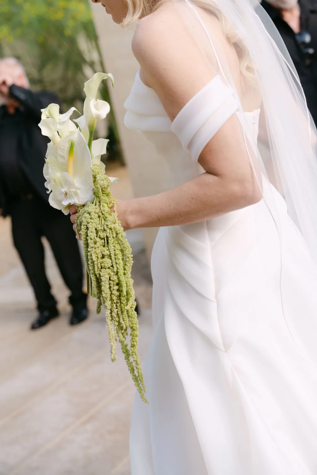 The calla and amaranthus bouquet held against the gown