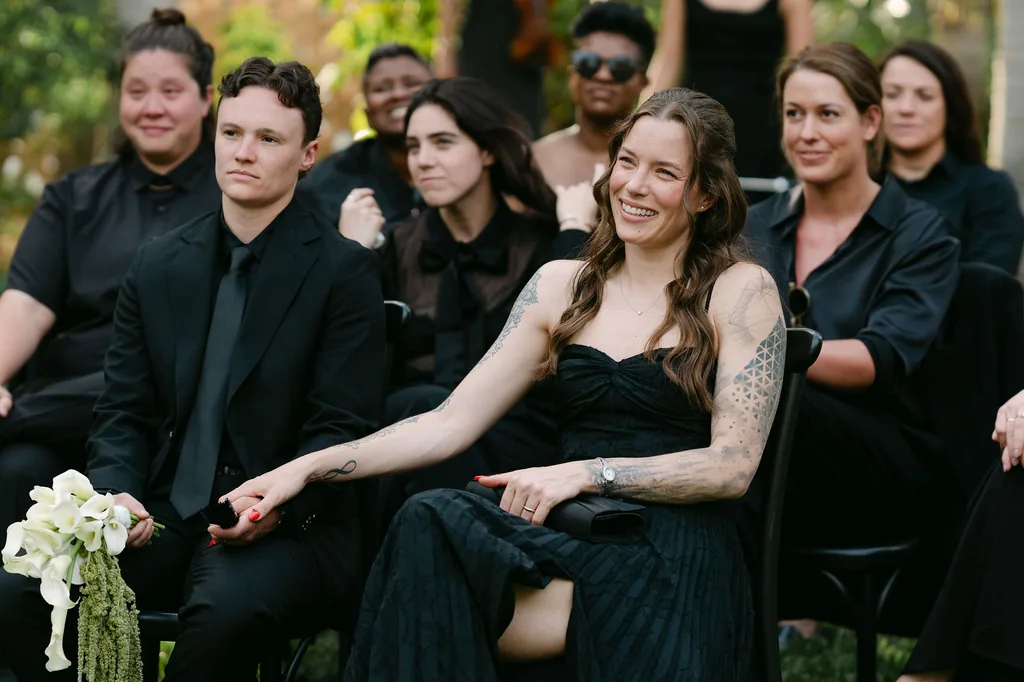 The guests in black, one of them holding the callas