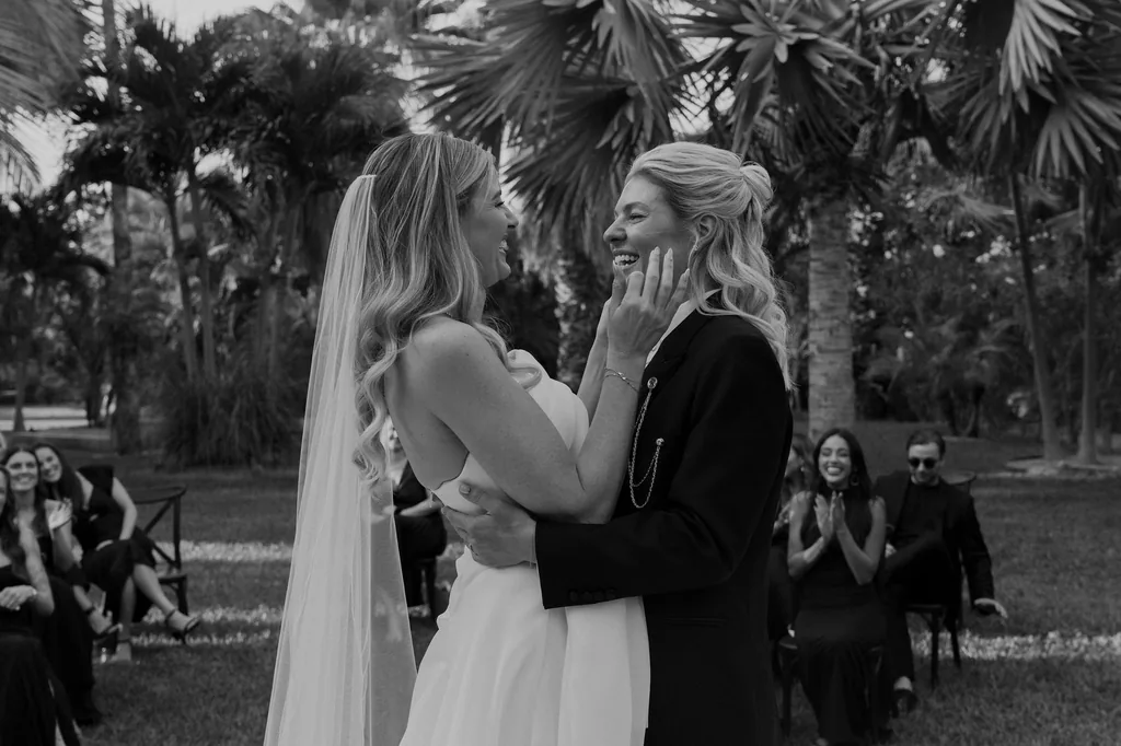 Emma and Whitney at the ceremony, a hand on her face, in black and white