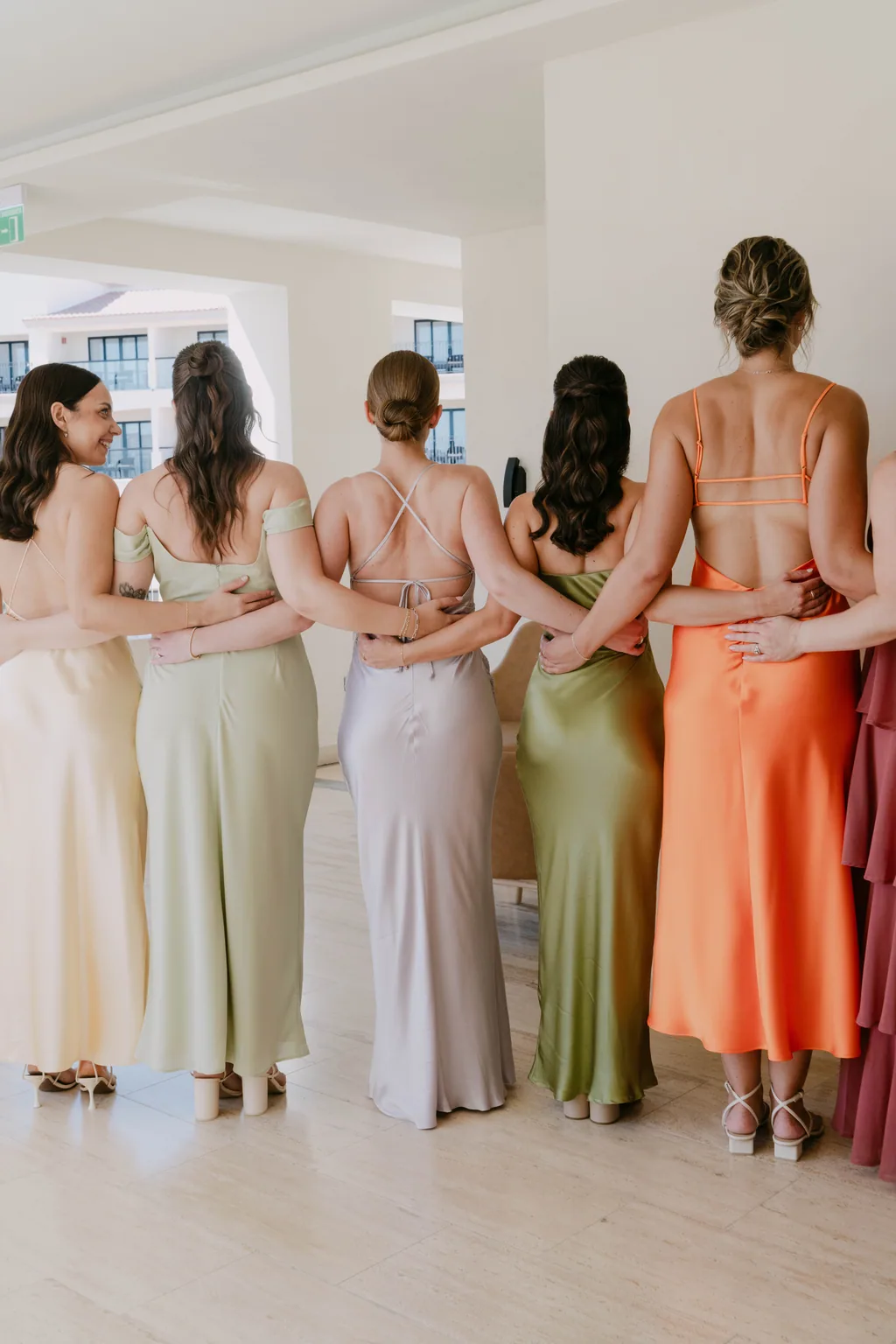 The bridesmaids from behind, in butter, blush, sage, coral and wine silk