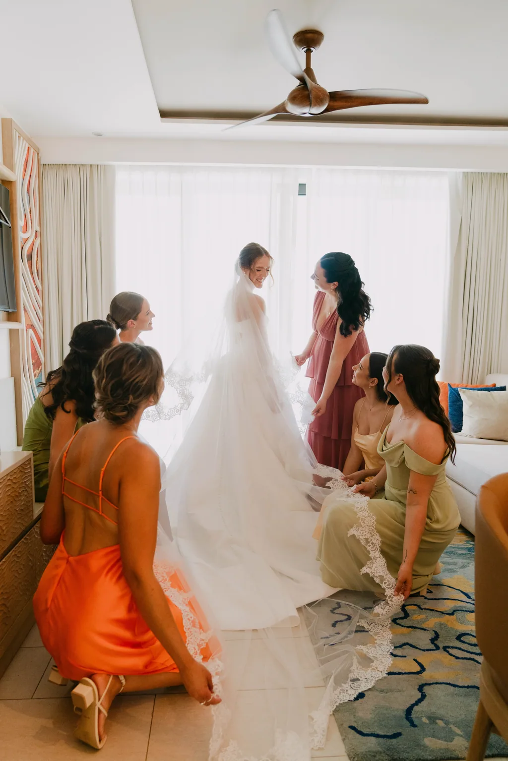 The bridesmaids kneeling around Lauren to arrange her dress