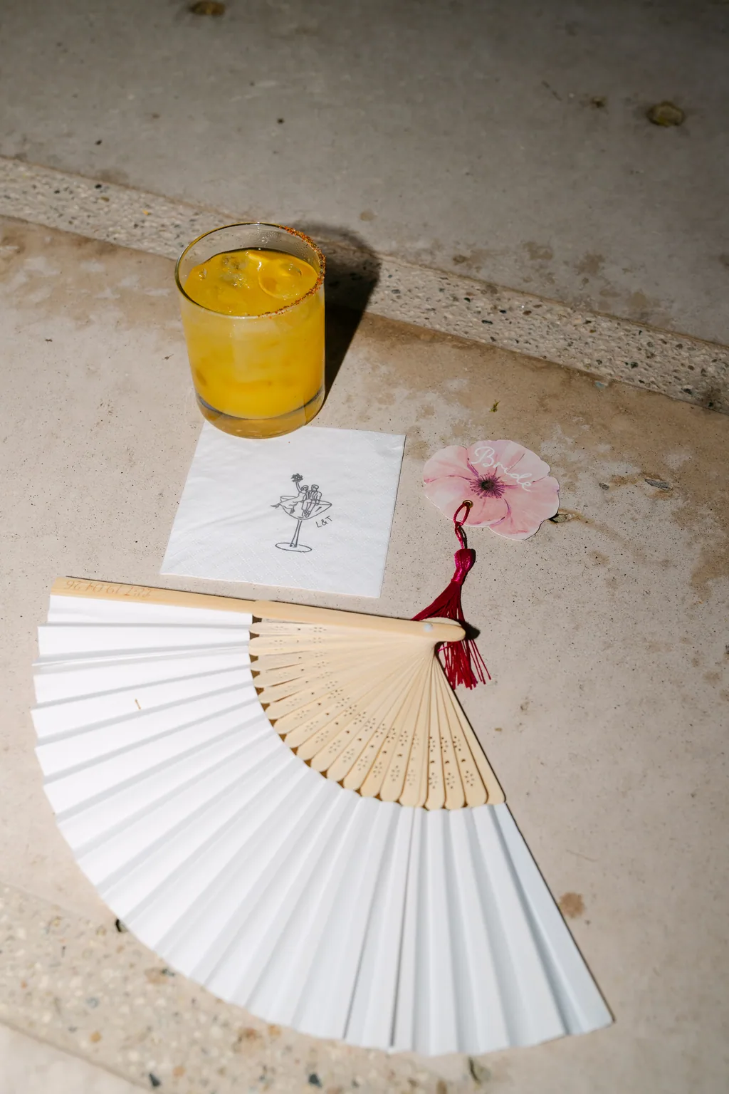A paper fan, a yellow drink and the ceremony programme