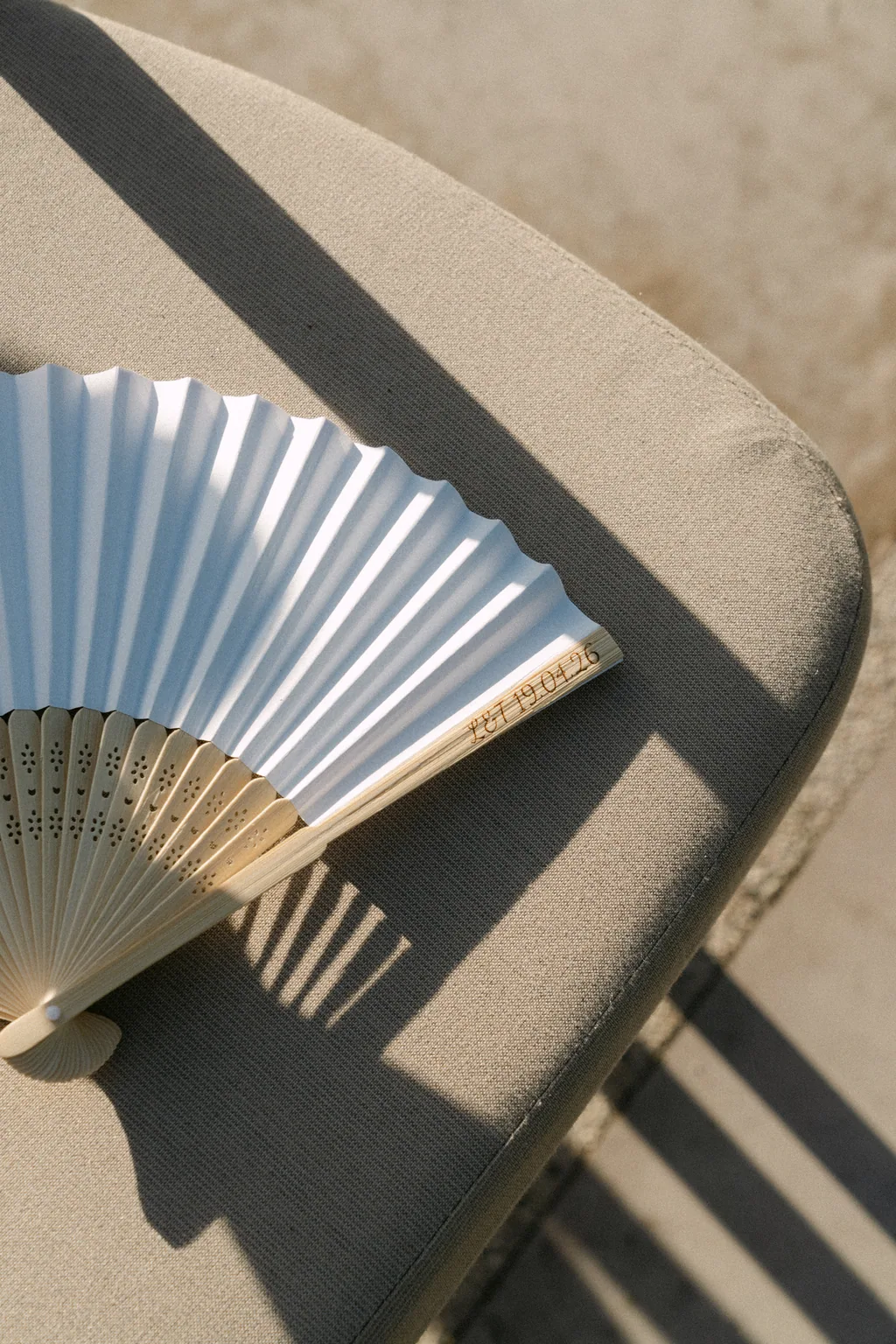 A pale blue paper fan on the stone, with the shadow of the afternoon across it