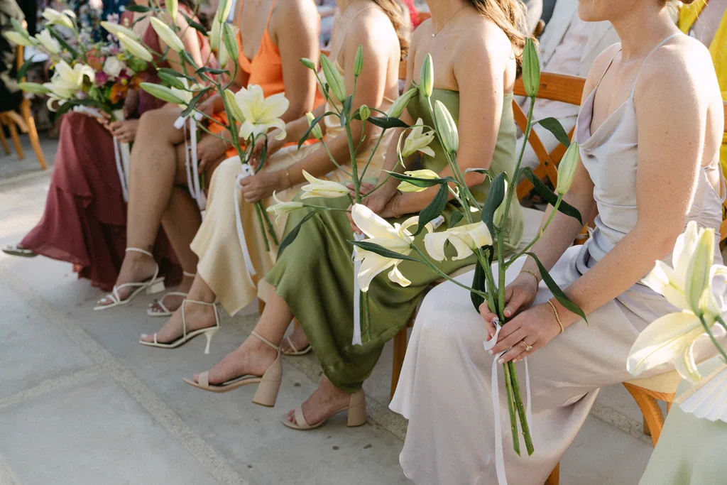 The bridesmaids seated with their lilies across their laps during the ceremony