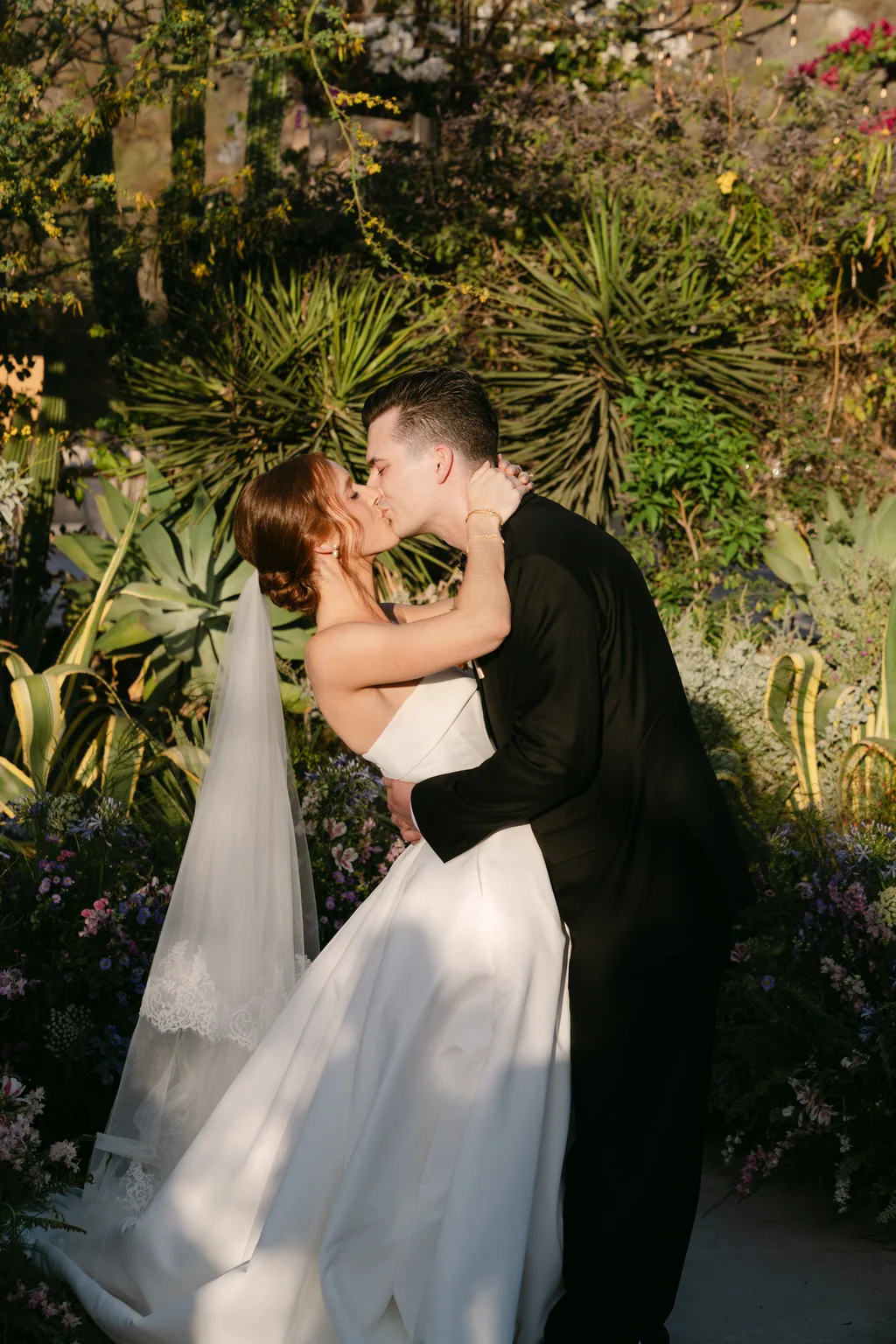 Lauren and Tevyn kissing in the aisle, surrounded by the garden