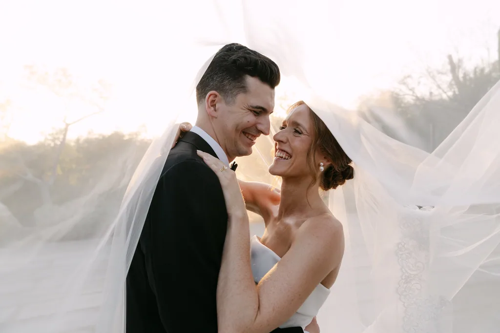 Lauren and Tevyn laughing under her veil in the late sun at Acre, San José del Cabo