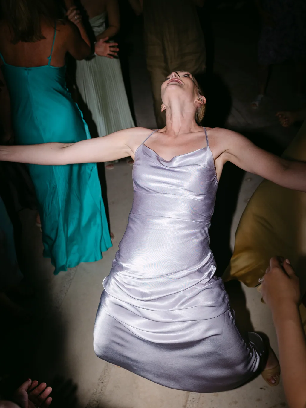 A guest in silver silk laughing with her head thrown back