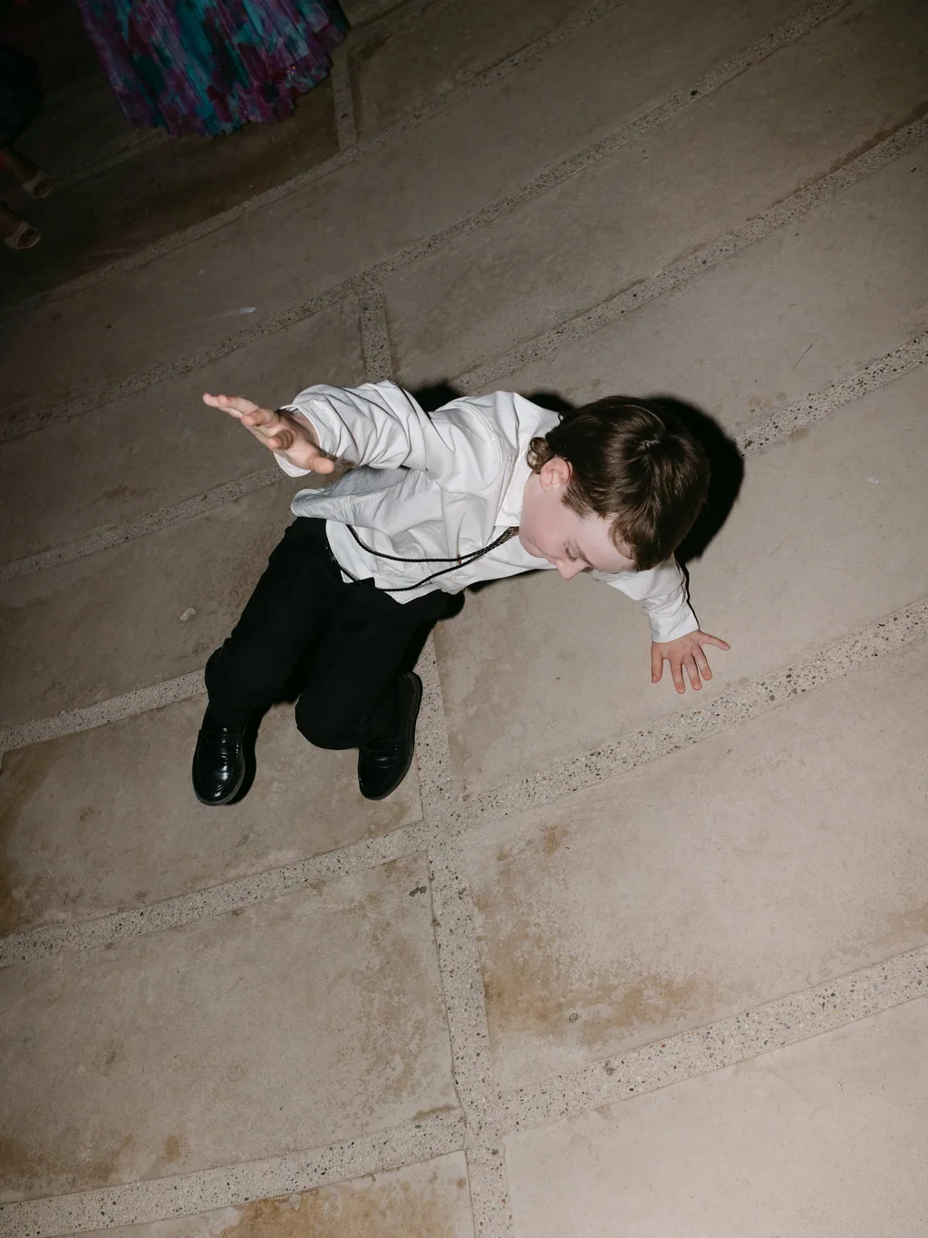 A boy in a tuxedo caught mid-air on the dance floor