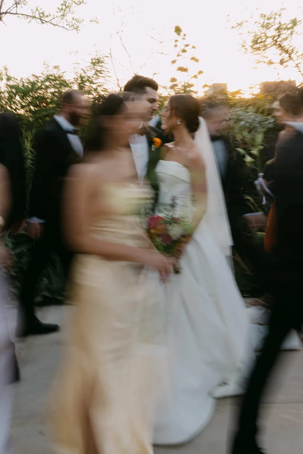 Lauren and Tevyn still while the wedding party blurs past them